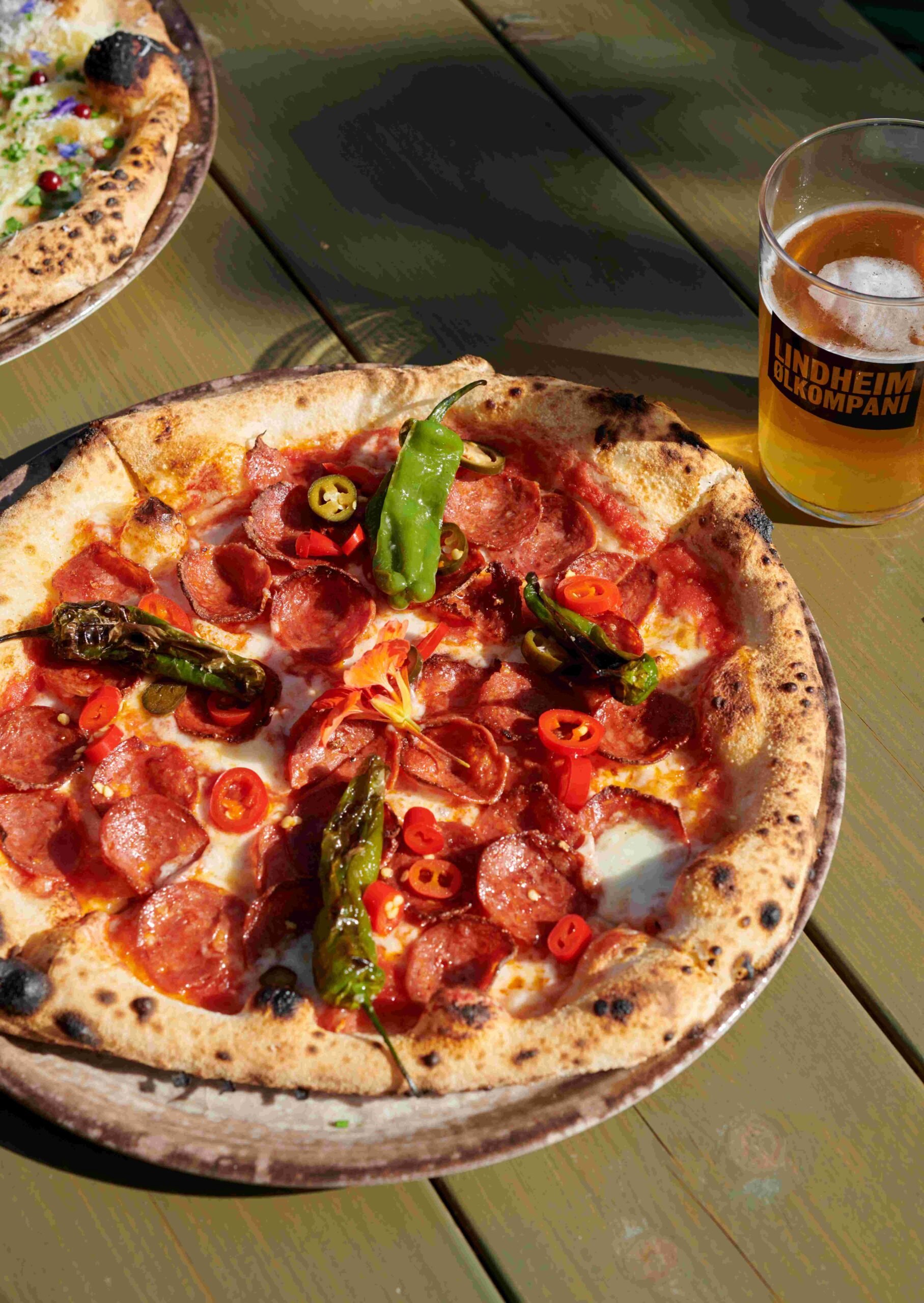 Delikat pizza med pepperoni, jalapeños og grønn paprika, servert med en kald øl fra Lindheim Ølkami.
